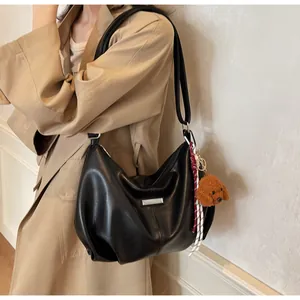 Détail du sac à épaule en cuir noir avec garniture argentée et charme de chien peluche