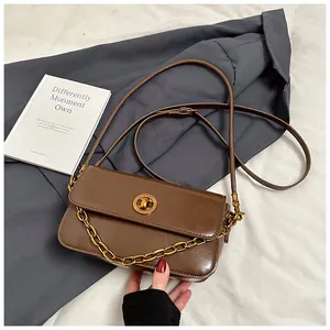 Detail of vintage brown rectangular shoulder bag with golden twist lock and metal chain