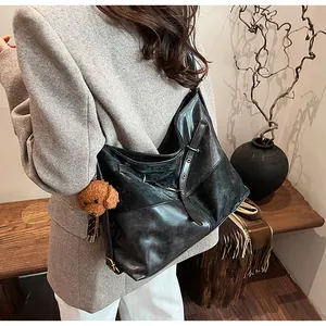 Vue détaillée d'un sac hobo noir porté à l'épaule avec pendentif chien en peluche