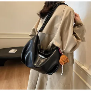 Détail du sac cabas en similicuir noir avec breloque peluche et ruban à rayures stylé