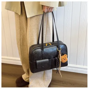 Detail view of vintage dark brown shoulder bag featuring dual front pockets and bear charm