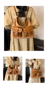 Detail of a large brown suede multi-pocket bag worn over the shoulder with a beige coat