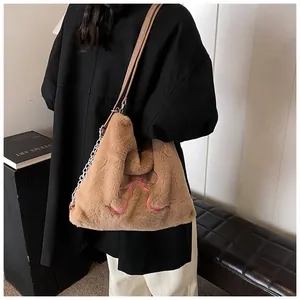 Dettaglio della borsa tote in peluche marrone con ricamo rosa e catena metallica