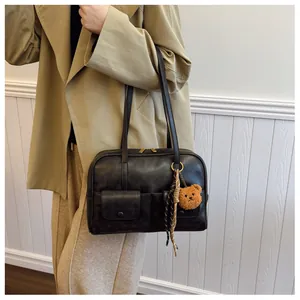 Detail of black vintage shoulder bag with textured PU leather and cute bear charm