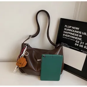 Vue détaillée du sac hobo marron avec charm ours et tablette pour référence de taille
