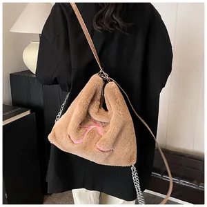 Dettaglio della borsa tote in peluche con ricamo a fiocco rosa e tracolla a catena