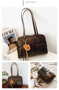 Detail view of a vintage dark brown shoulder bag with front pockets and plush bear charm