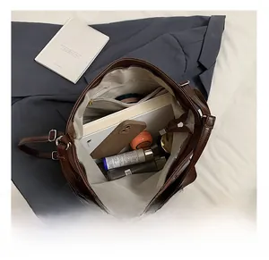 Interior detail of large brown tote bag showing multi-pocket storage for books and phone