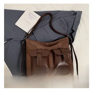 Detail view of large brown crossbody bag featuring suede finish and dual utility pockets