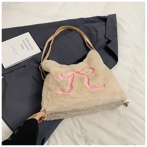Dettaglio borsa di peluche con ricamo fiocco rosa e tracolla in pelle marrone