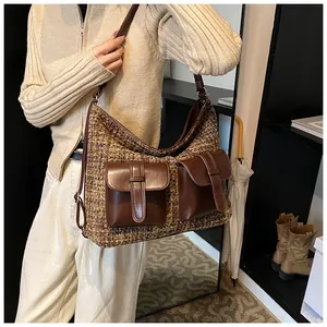 Detail of tweed hobo bag featuring brown faux leather pockets and textured weave