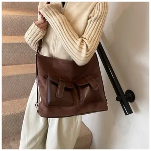 Detail of vintage brown suede shoulder bag with dual leather pockets and strap buckles