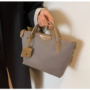 Close-up of taupe oxford tote bag with leather handles and a side pouch accessory