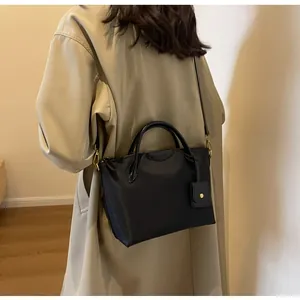 Detail shot of black Oxford fabric shoulder bag featuring elegant top handles and leather logo