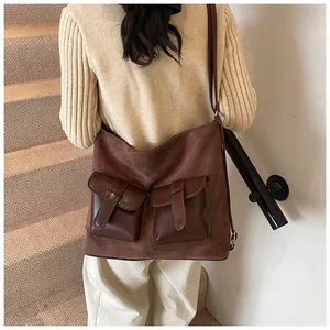 Detail of dark brown multi-pocket bag with suede texture and glossy leather flaps