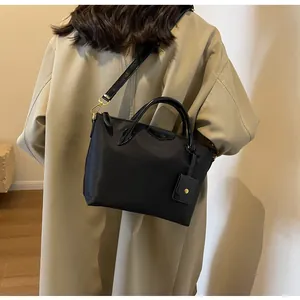 Detail of black oxford tote bag with leather handles and small pouch accessory
