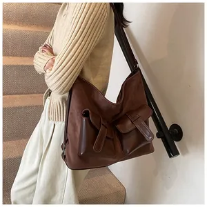 Detail of large brown suede messenger bag with dual leather front pockets and buckles