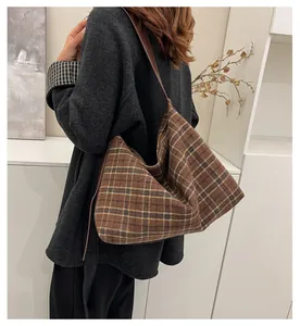 Détail d'un grand sac hobo à carreaux marron avec bandoulière en cuir sur un mannequin