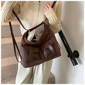 Detail view of large brown crossbody bag with multi-pocket design on model