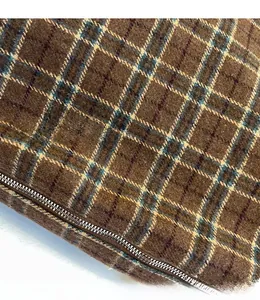 Gros plan sur la texture en laine à carreaux marron et le détail du zip métallique