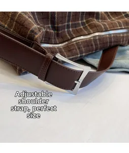 Détail de la bandoulière réglable avec boucle argentée sur un sac cabas à carreaux brun