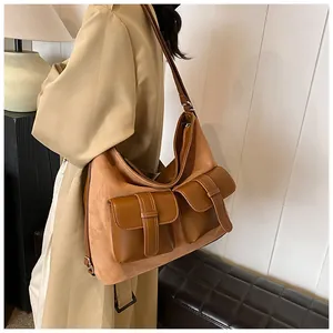 Detail of tan multi-pocket tote bag with suede contrast worn by model on shoulder