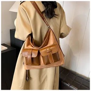 Detailed view of large brown suede and leather crossbody bag styled with a khaki trench coat