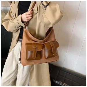 Detail of a brown suede hobo bag with flap pockets and adjustable strap on a model