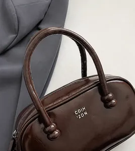 Detailed close-up of dark brown glossy leather handbag handles with spherical hardware