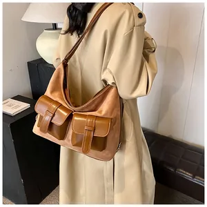 Detail of vintage brown suede crossbody bag with double utility flap pockets and strap