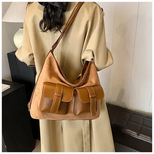 Side view of large camel suede crossbody bag with multiple pockets worn by a model
