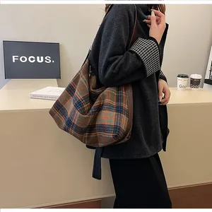 Détail d'un sac à bandoulière à carreaux vintage avec bandoulière en cuir marron foncé