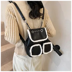Vista trasera de una mochila de cuero negro con ribete de felpa blanca en una modelo