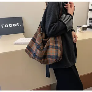Détail du sac fourre-tout en tweed à carreaux avec bordure en cuir et nœud à la bandoulière