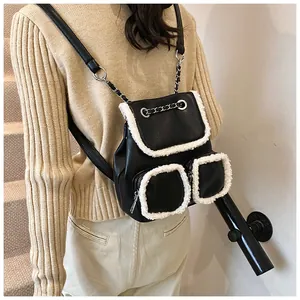 Detalle de mochila de cuero negro con ribete de piel blanca y correas de cadena