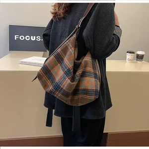Détail d'un sac hobo à carreaux vintage avec bandoulière réglable en cuir marron sur modèle