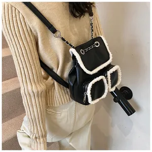 Detalle de mini mochila en cuero sintético negro con ribete de felpa blanca