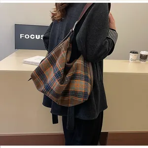 Gros plan du sac cabas en laine à carreaux orange avec bandoulière en cuir marron