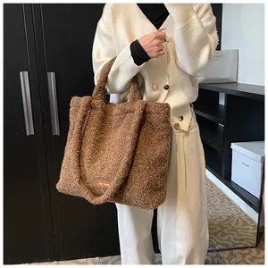 Dettaglio della trama della borsa tote in peluche marrone con etichetta tessuta 'our fave' morbida
