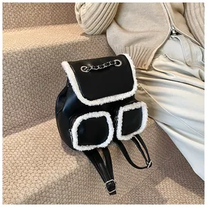 Detalle de mochila de cuero negro con ribete de lana blanca y cadena de metal plateada