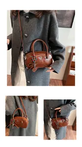 Detail view of caramel brown leather boston bag with charms and brand logo on model
