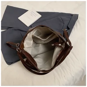 Detail view of large brown tote bag interior with gray lining and multiple pockets