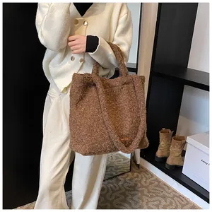 Dettaglio macro della borsa tote marrone in peluche con etichetta logo in pelle e pelo