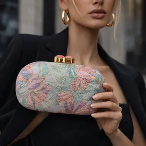 Detail of elegant floral embroidered clutch with gold clasp and pink stones on top