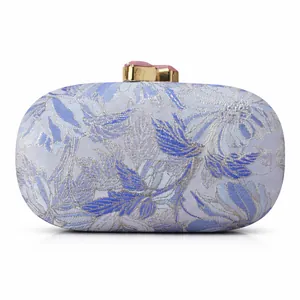 Detail of blue floral jacquard evening clutch with golden clasp and pink gemstone