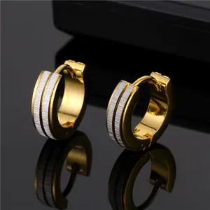 Macro view of two-tone huggie earrings with gold finish and silver brushed textures