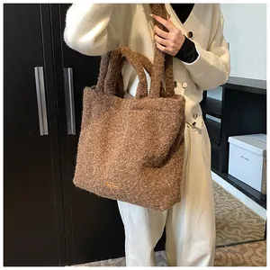 Dettaglio della borsa tote in peluche marrone con logo arancione e manico spesso
