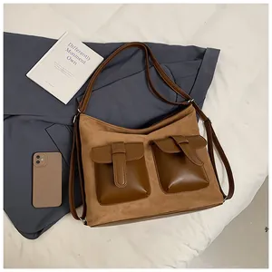 Detail of vintage brown suede shoulder bag with dual leather flap pockets and silver buckles