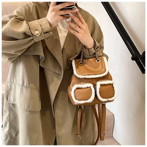 Mochila de cuero marrón con ribete de felpa blanca lucida por modelo en gabardina caqui
