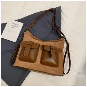 Detail of vintage brown suede shoulder bag with dual buckle pockets and sleek leather contrast